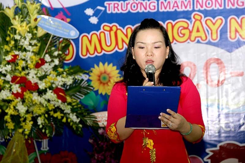 Cô giáo mặc áo dài đỏ đọc bài phát biểu trong lễ chào mừng 20/11