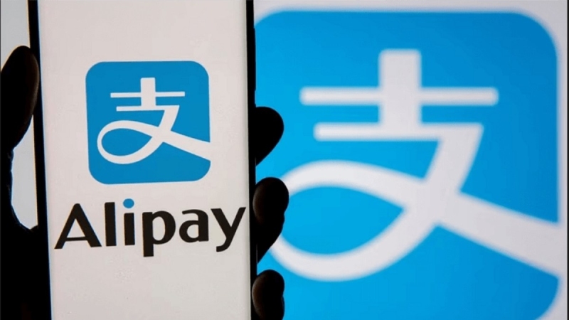 Người dùng cầm điện thoại hiển thị logo Alipay trên màn hình