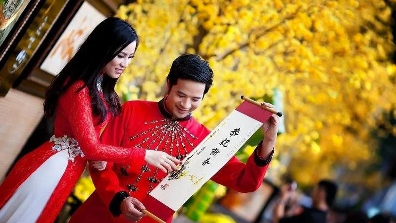 Cặp đôi diện áo dài xem câu đối ngày Tết