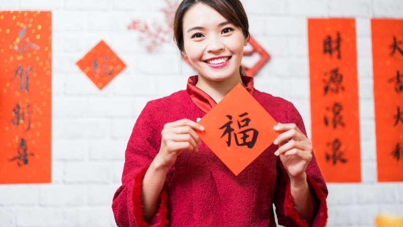 Cô gái cầm chữ Phúc trong không gian trang trí Tết